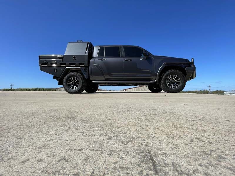 A black truck with a flat bed is parked on the side of the road.