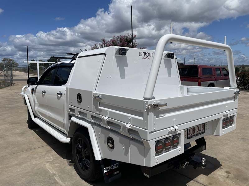A white truck with a toolbox on the back is parked on the side of the road.