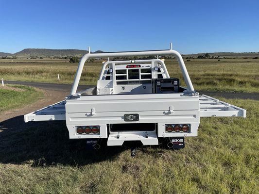 A white truck is parked in a grassy field next to a road.