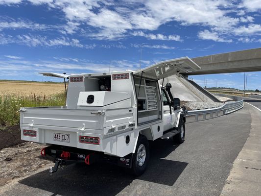 A white truck is parked on the side of the road with its trunk open.