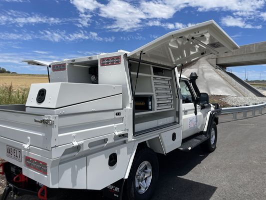 A white truck with the hood open is parked on the side of the road.
