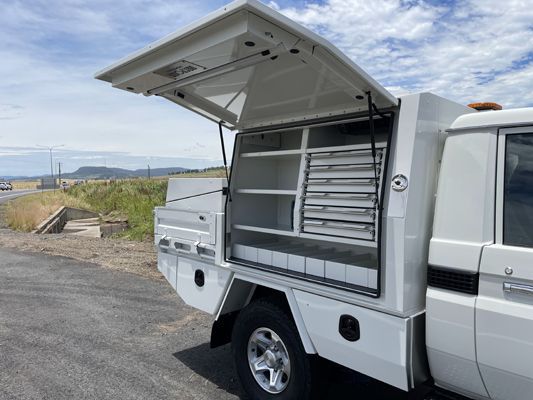 A white truck with the trunk open is parked on the side of the road.