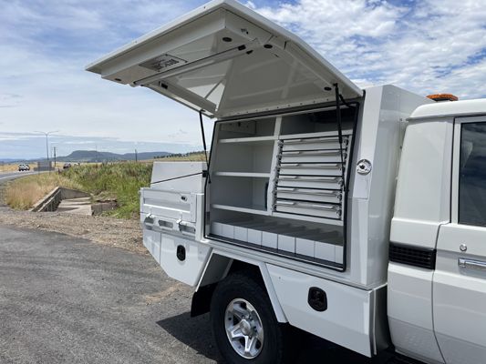 A white truck with the trunk open is parked on the side of the road.