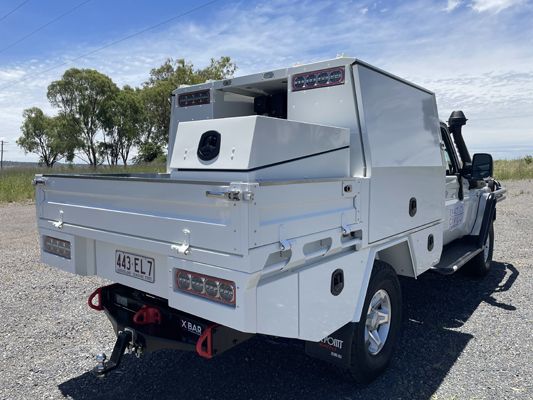 A white truck is parked in a gravel lot.