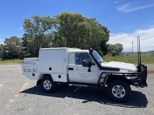 A white truck is parked in a gravel lot.