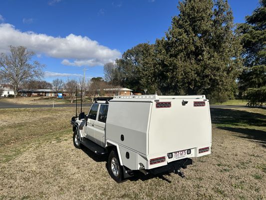 A white truck with a canopy is parked in a grassy field.