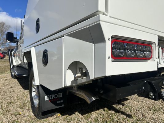 A white truck is parked in a grassy field.