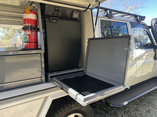 The inside of a truck with a refrigerator and a fire extinguisher.