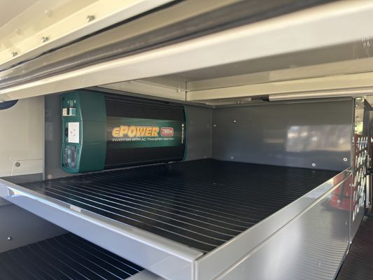 A green power inverter is sitting on top of a metal shelf.