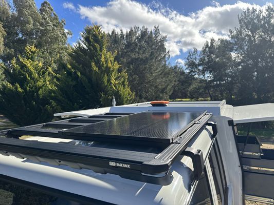 A white truck with a solar panel on the roof.