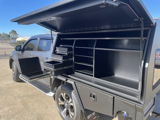 A black truck with the hood open and shelves inside