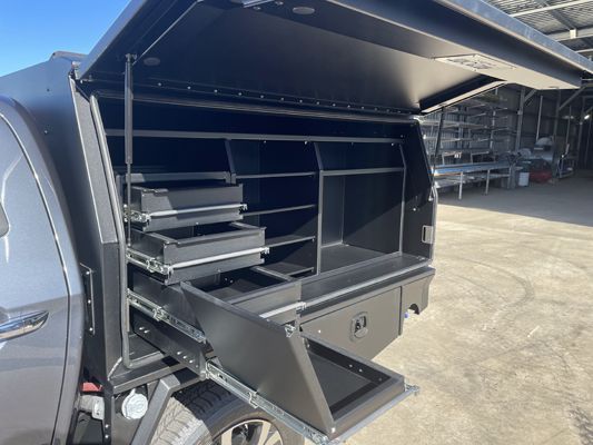The back of a truck with the canopy open and drawers.