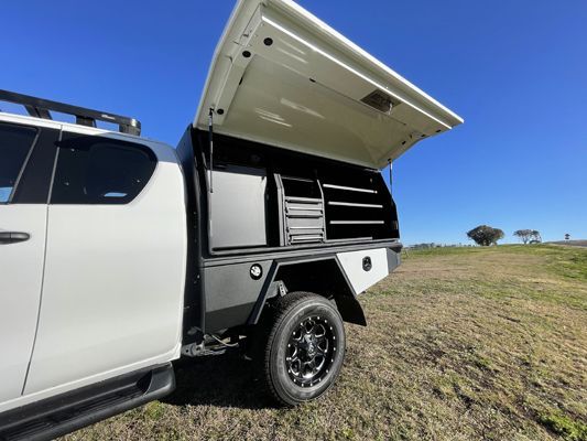 A white truck with the hood open is parked in a field.