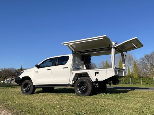 A white truck with a canopy is parked in a grassy field.