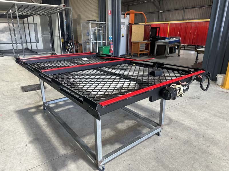 A metal table with wheels is sitting in a warehouse.