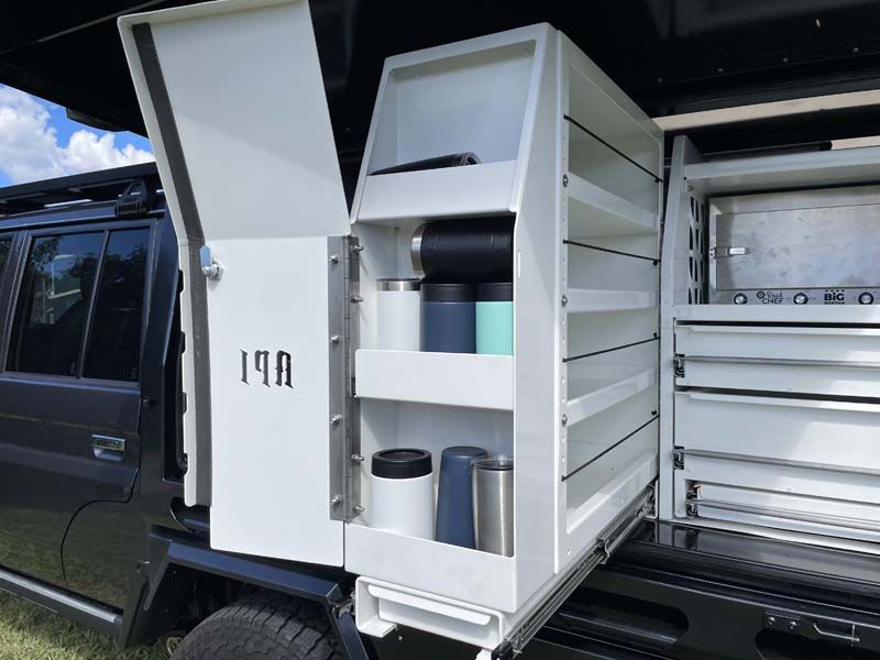 A black truck with a white cabinet in the back of it.