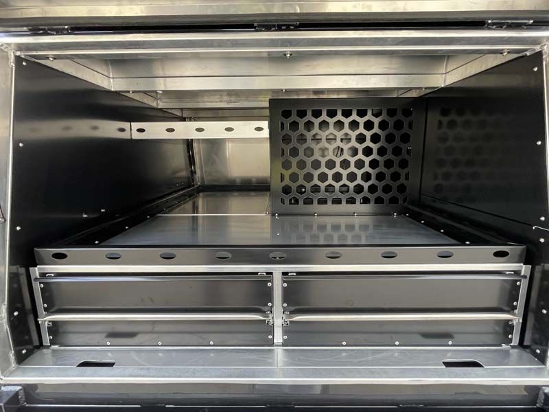 The inside of a stainless steel cabinet with drawers and a shelf.