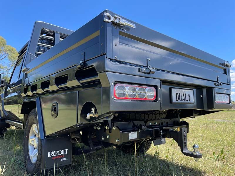 A black truck with a flat bed is parked in a grassy field.