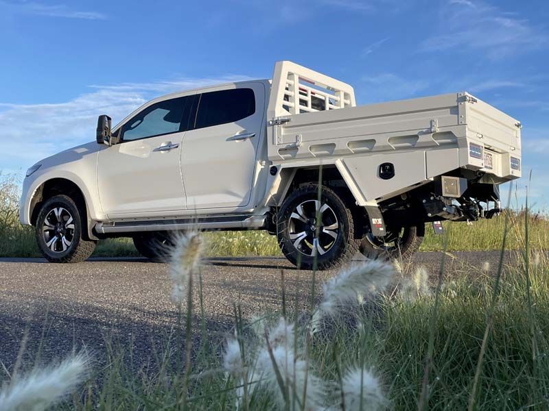 A white truck is parked on the side of the road next to a field of tall grass.