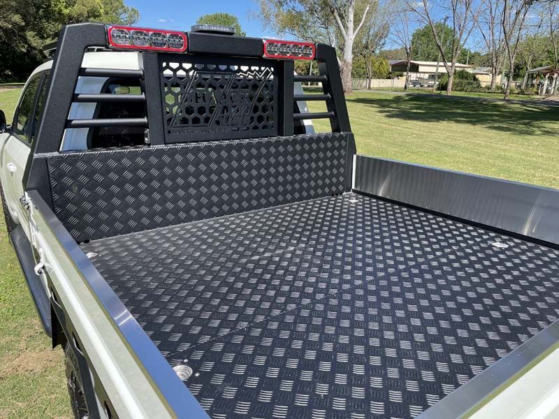 The back of a truck with a black tray and a headache rack.