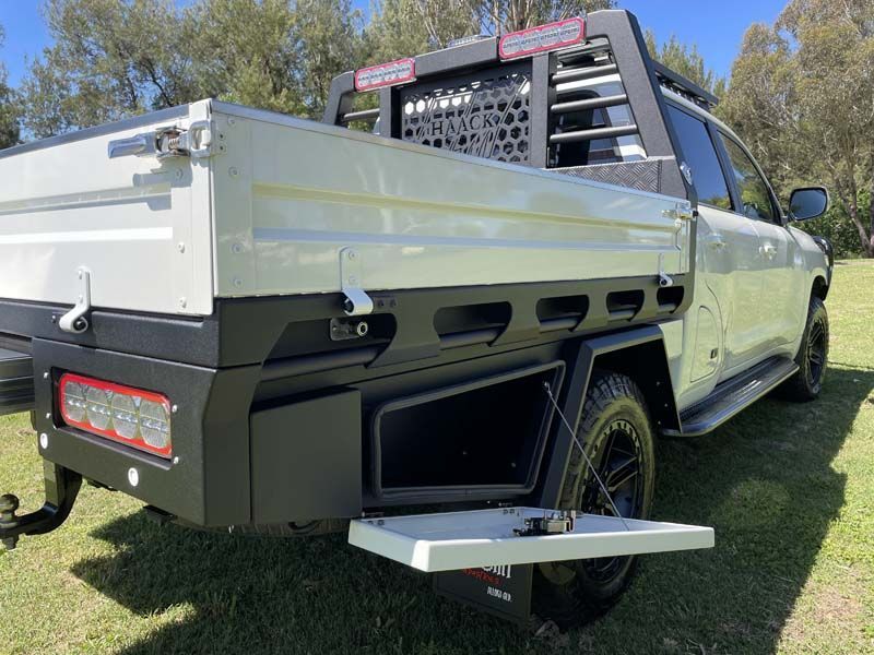 A white truck with a tray on the back is parked in a grassy field.