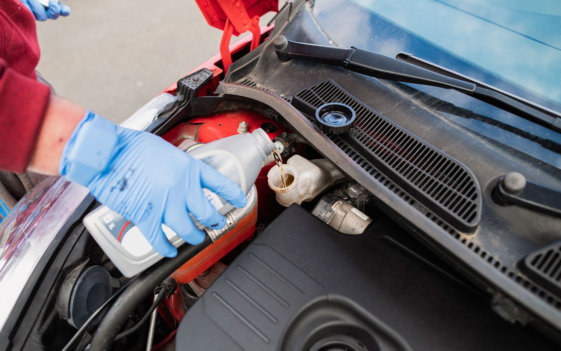 A person is pouring oil into the engine of a car.
