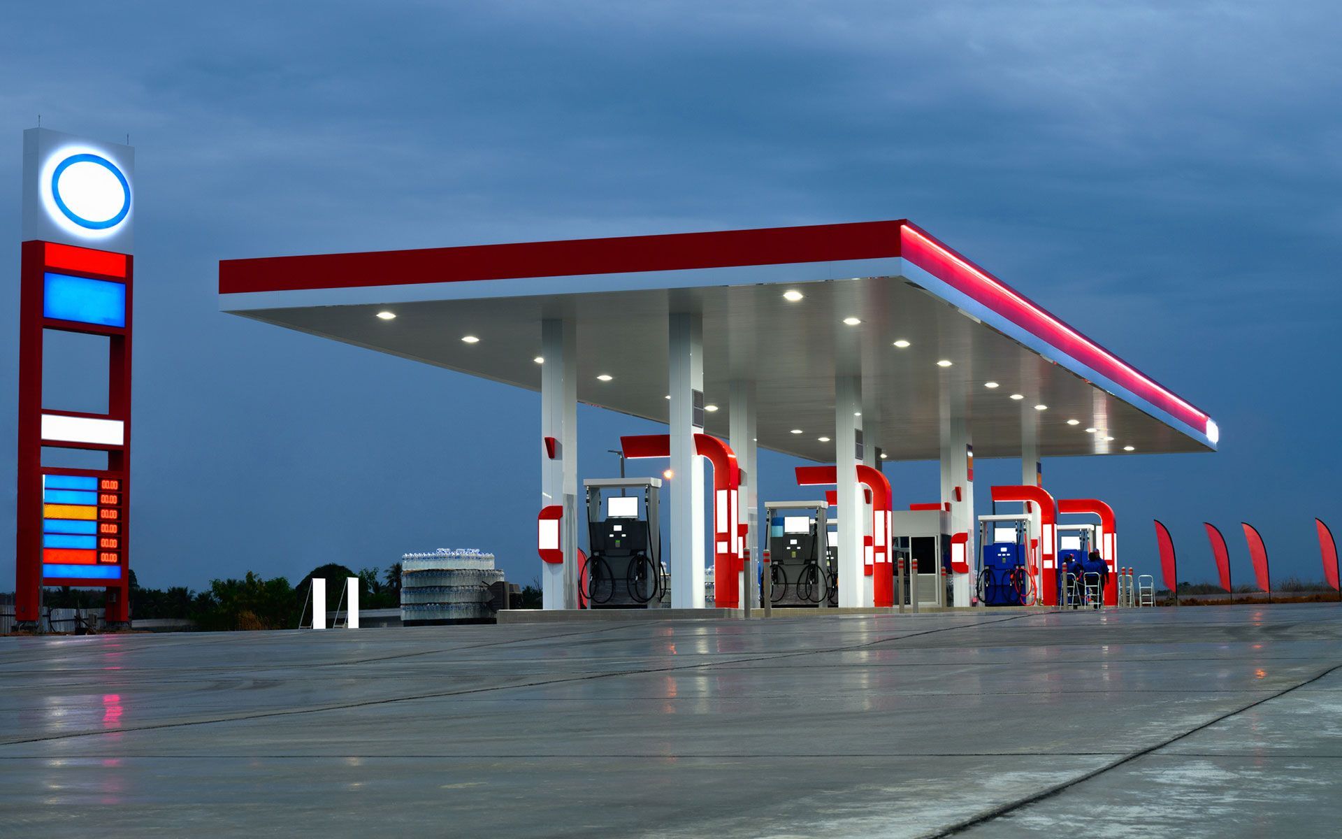 A gas station with a red and white roof at night.