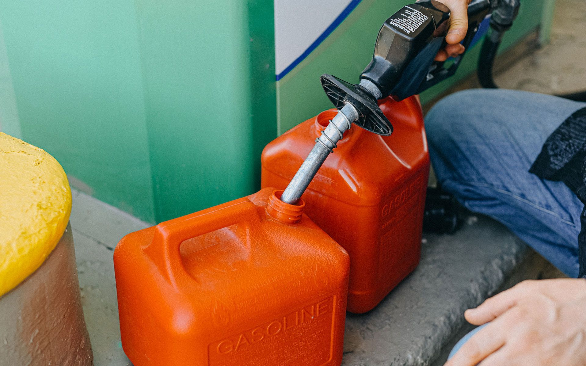 A person is pouring gas into a red gas can.