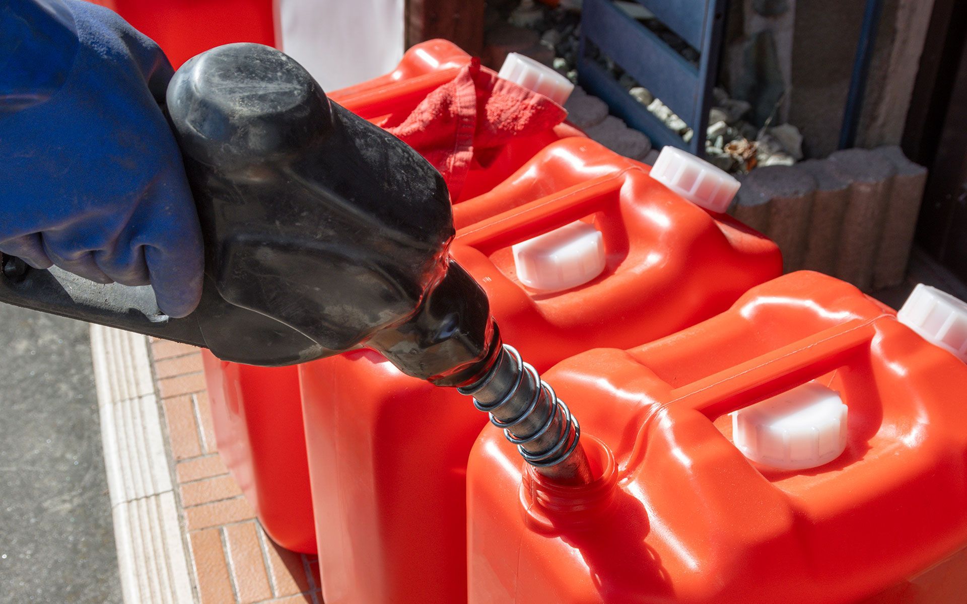 A person is pumping gas into a red jerry can.