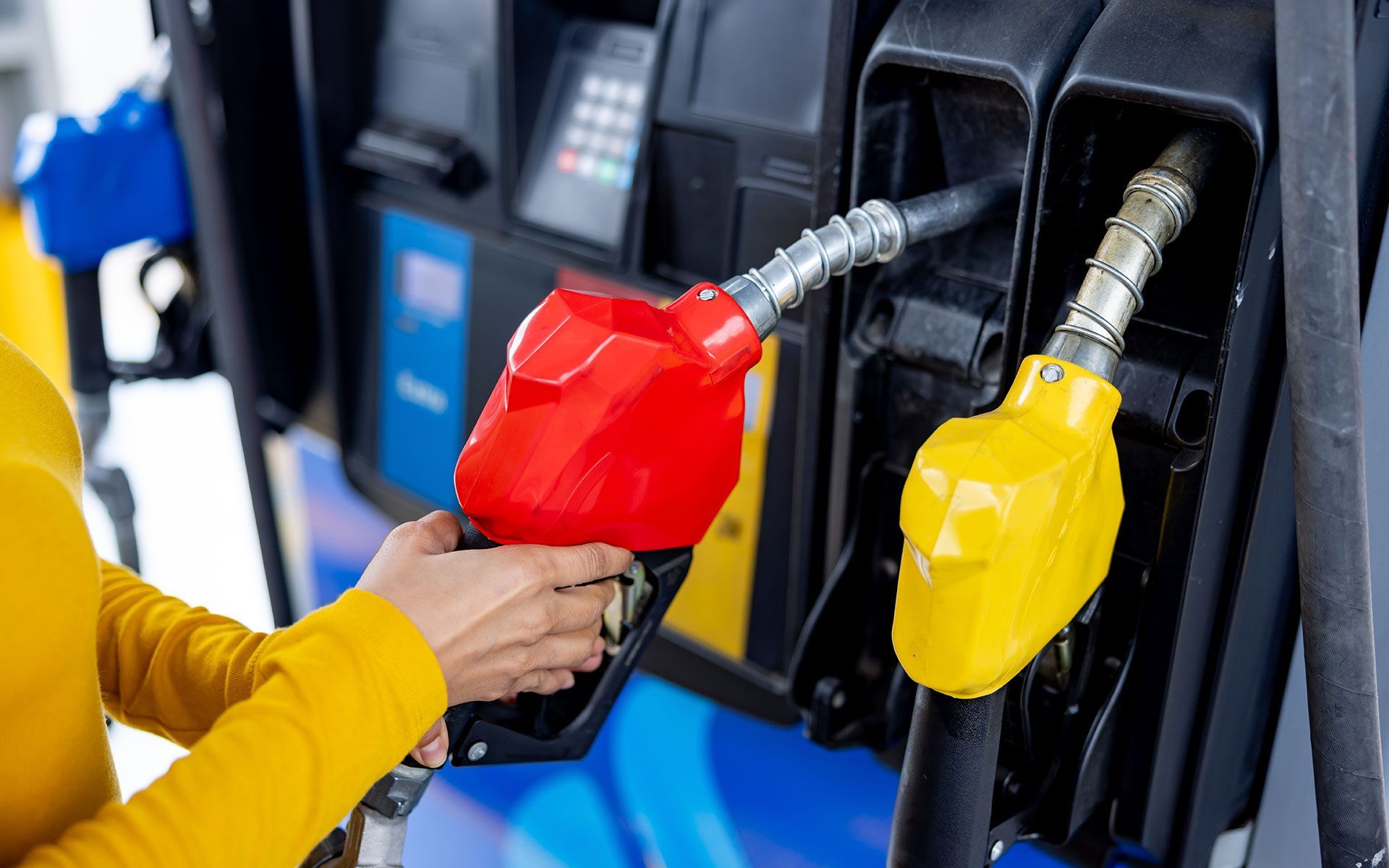 A woman is pumping gas into a gas pump at a gas station.