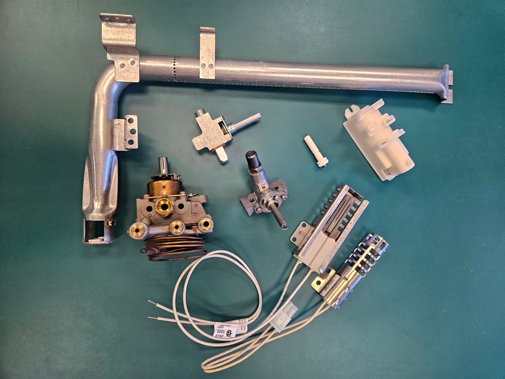 A white washing machine is sitting in front of a white brick wall.