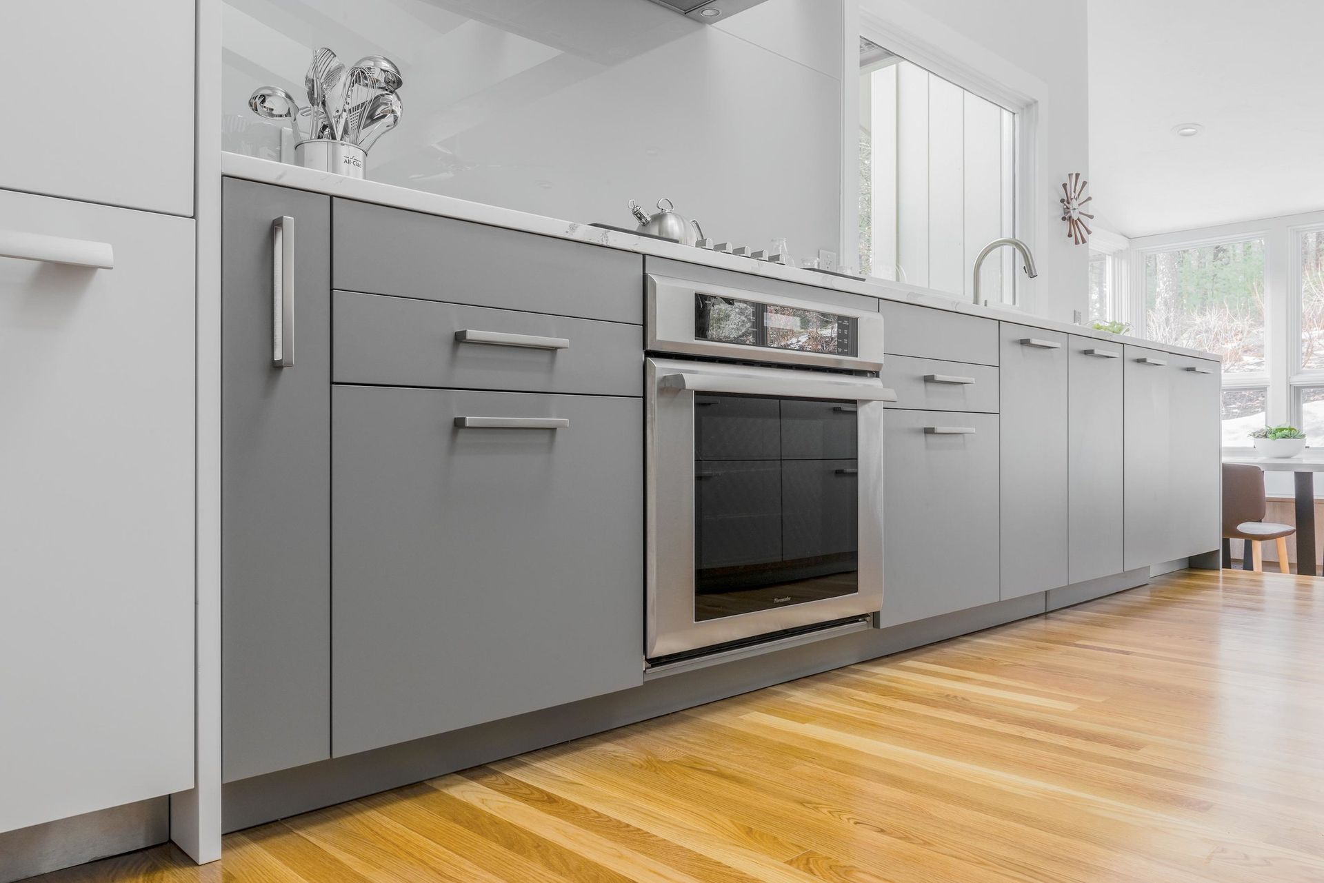 A kitchen with gray cabinets and a stainless steel oven.