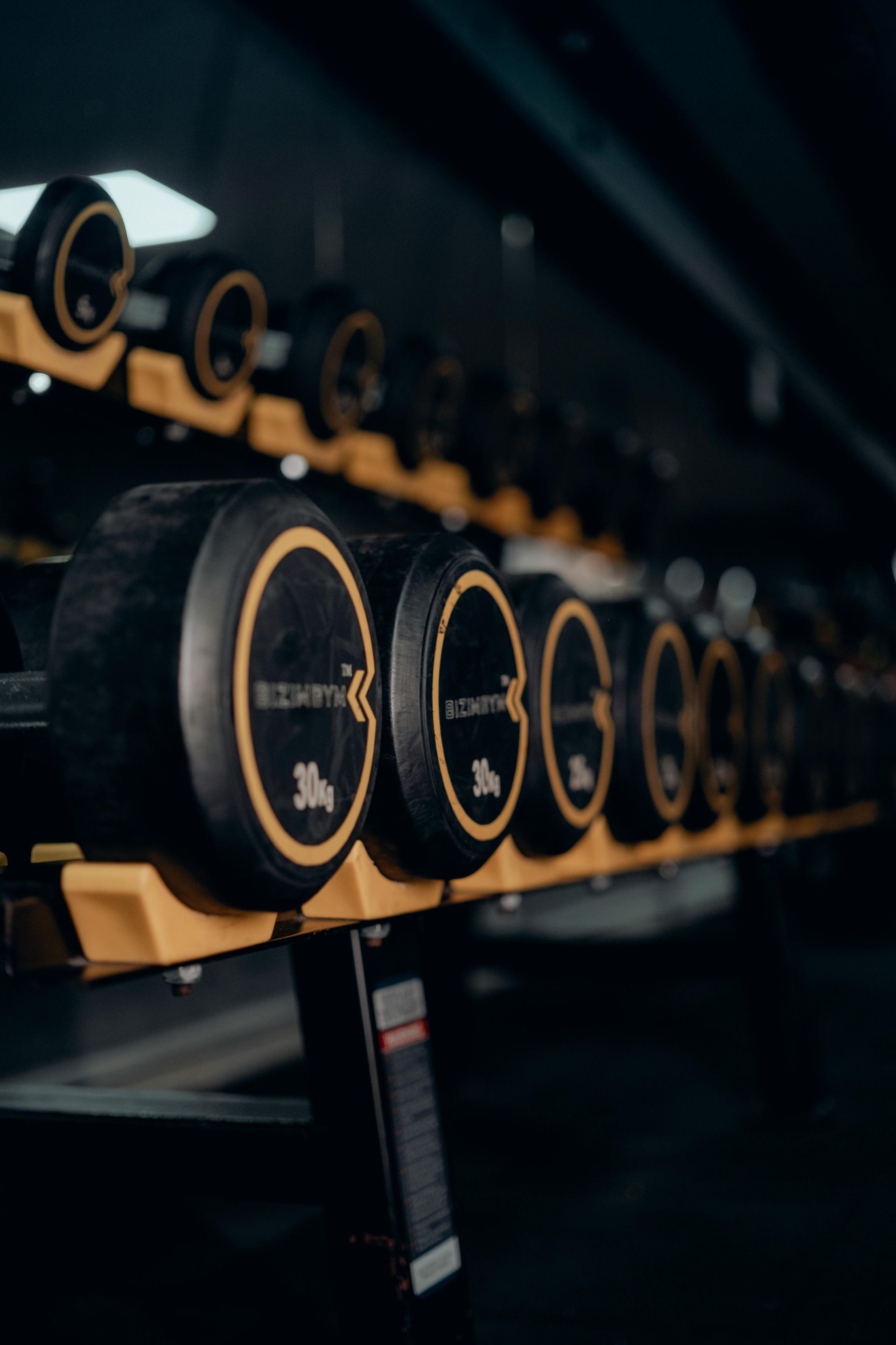 Een rij zwarte en gouden elektrische scooters staat geparkeerd op een donkere plank in een showroom.