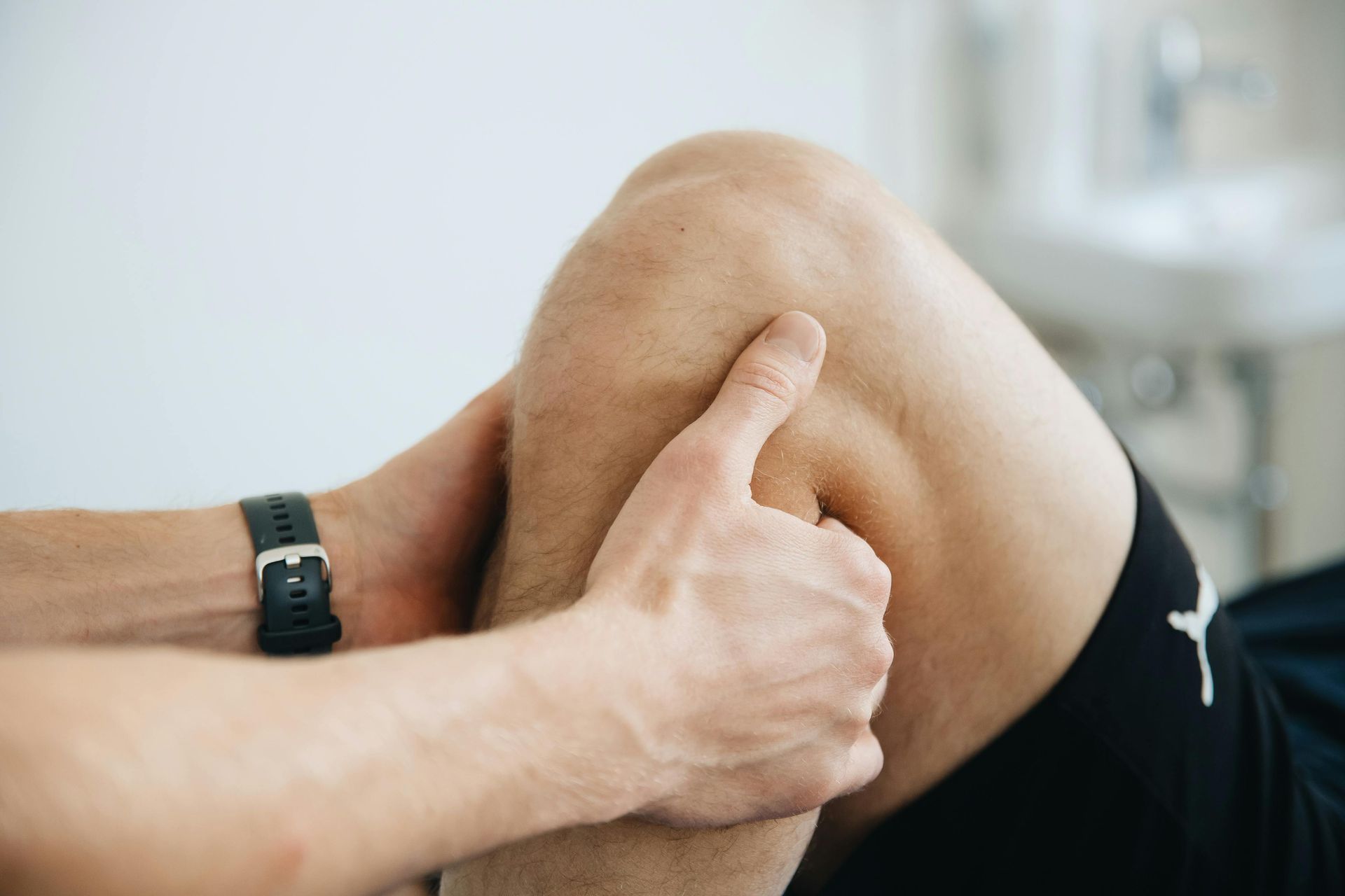 Handen onderzoeken een gebogen knie, wat wijst op een knieblessure of pijnbeoordeling.
