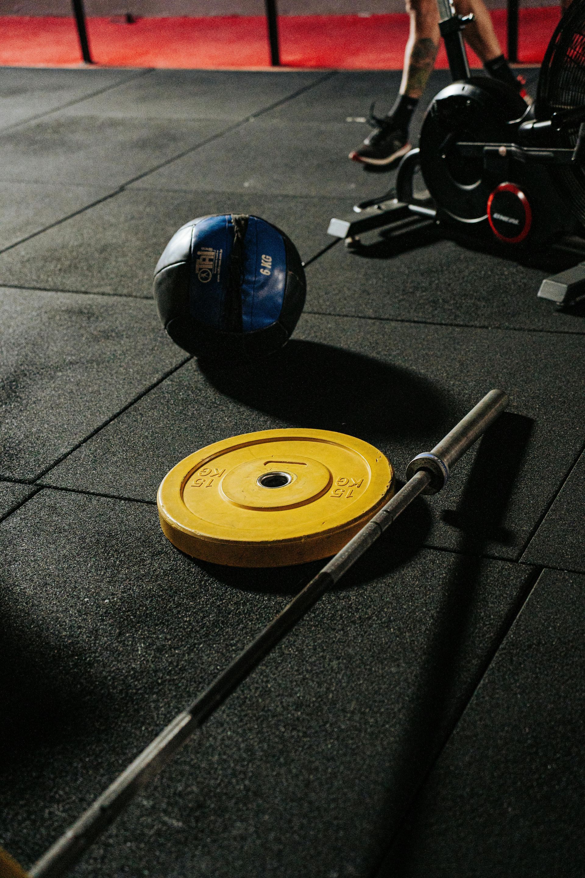 Gymvloer met halter, gele gewichtsschijf en medicijnbal in de buurt van fitnessapparatuur