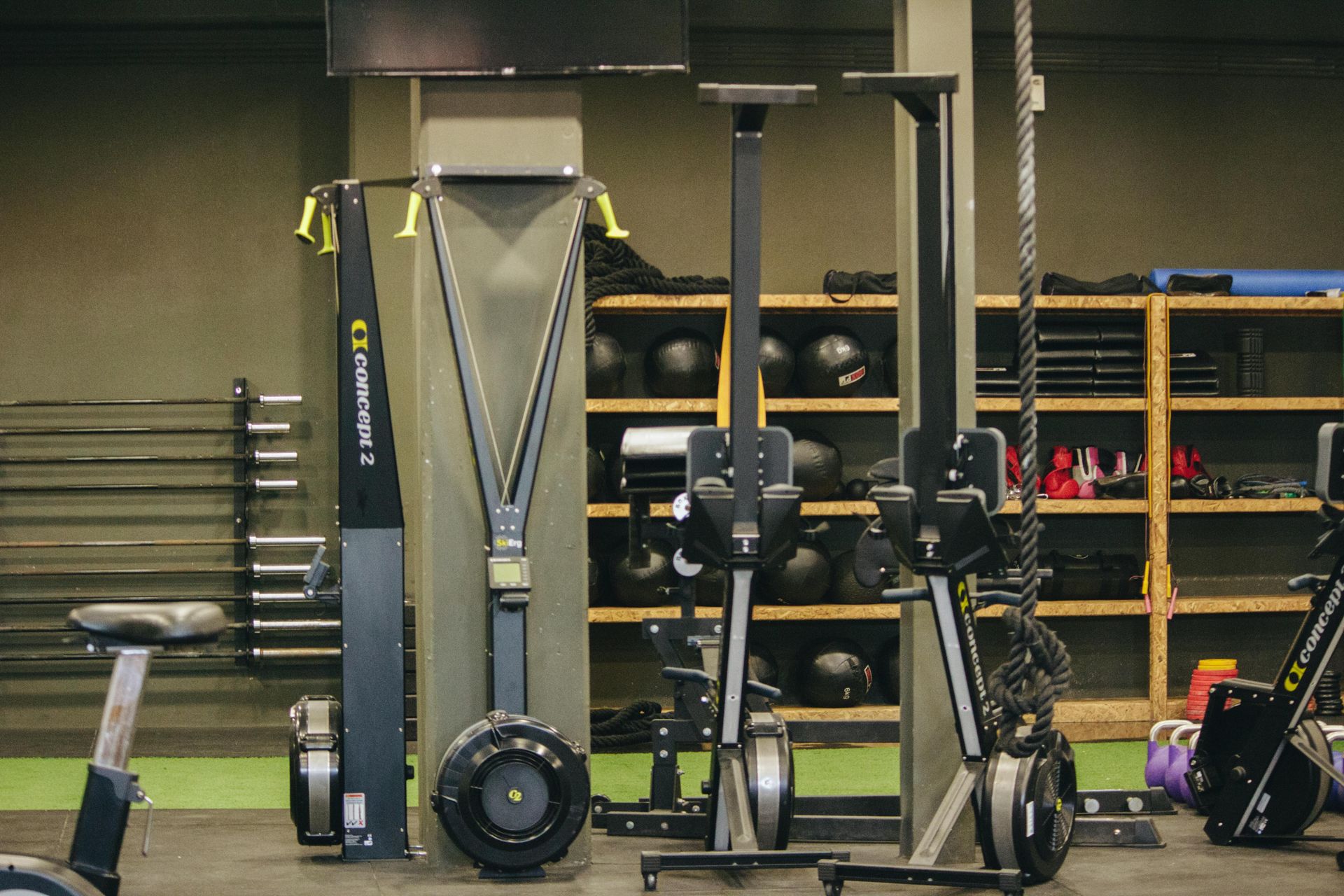 Fitnessapparatuur met een hometrainer en kabelmachines in een trainingsruimte.