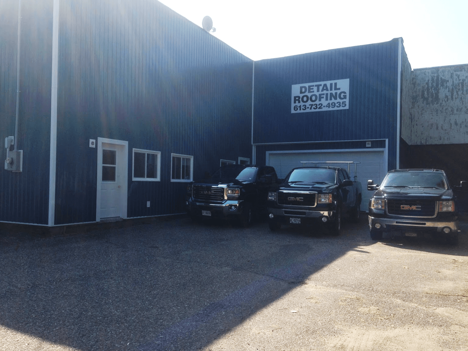 blue storefront with three black pickup trucks parked in front of it.