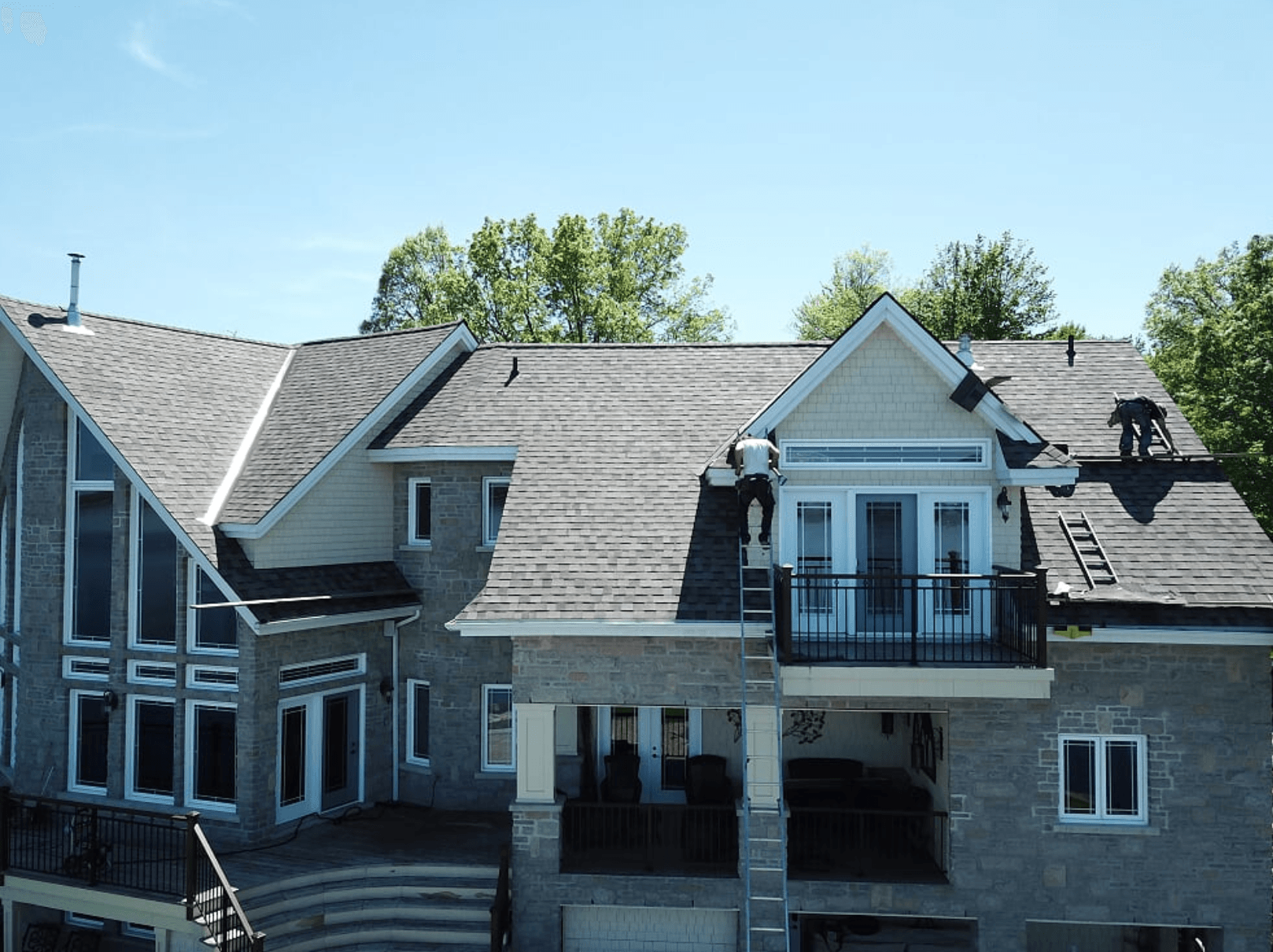 large grey brick house with gable and baller roof under construction