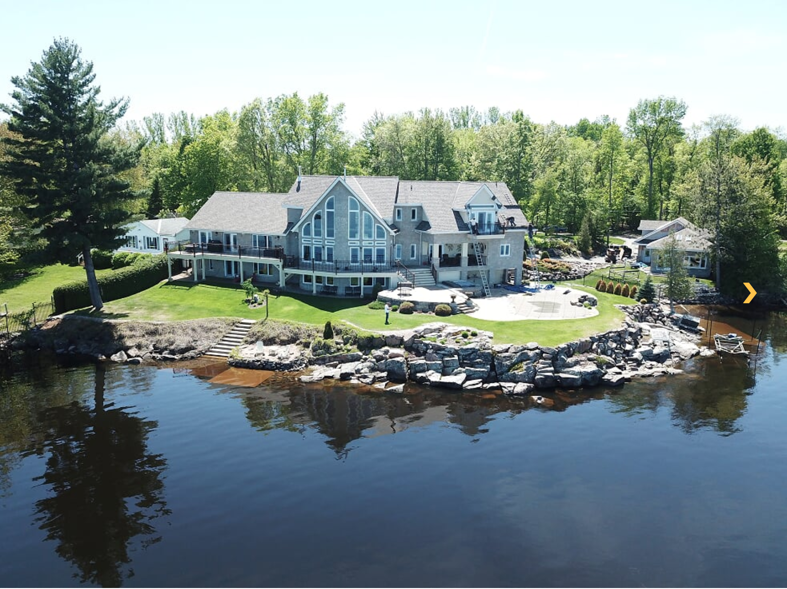 large white and grey lake-side house with gable and valler roof
