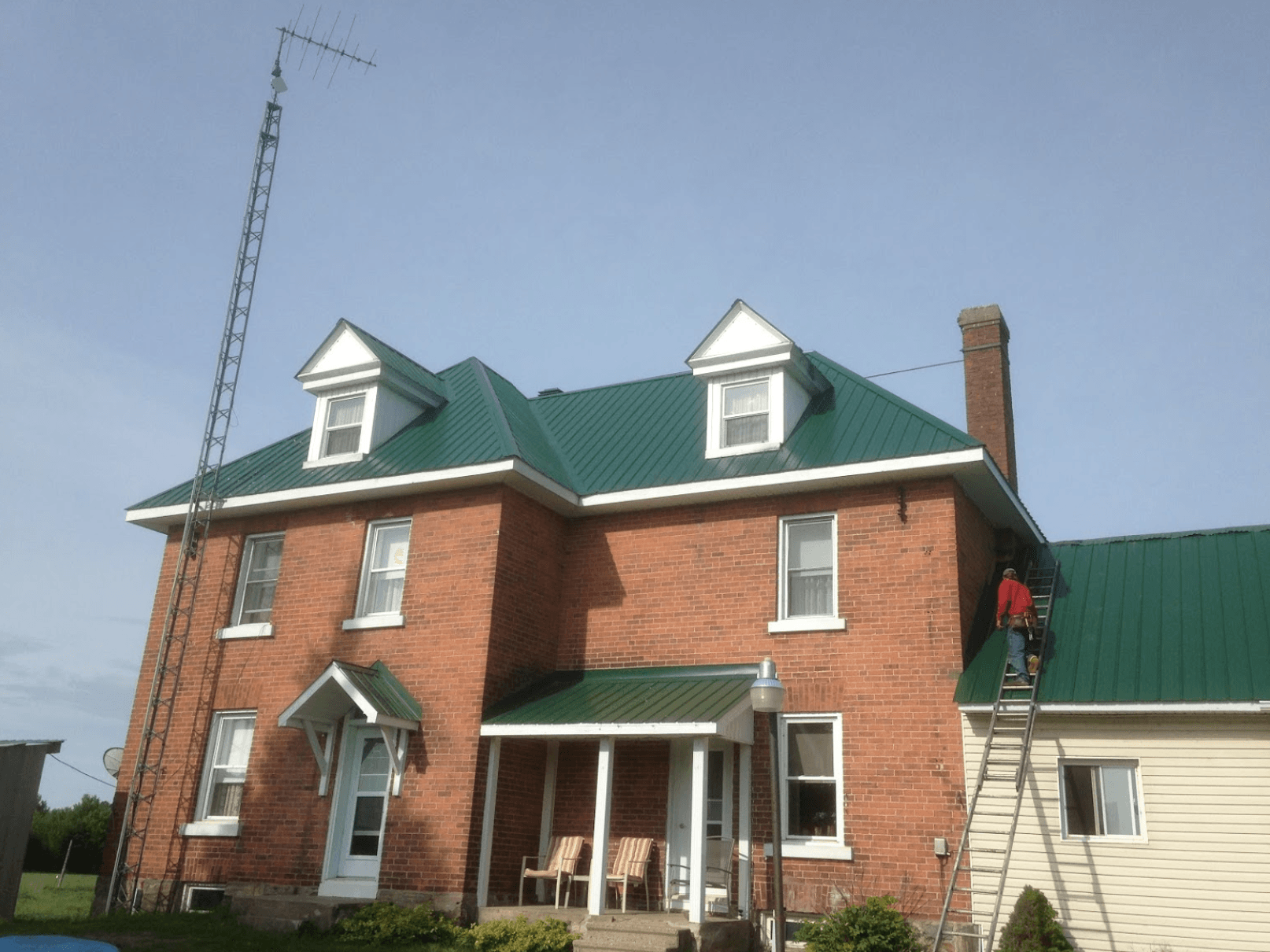 red brick building with green gable roof and dormer windows