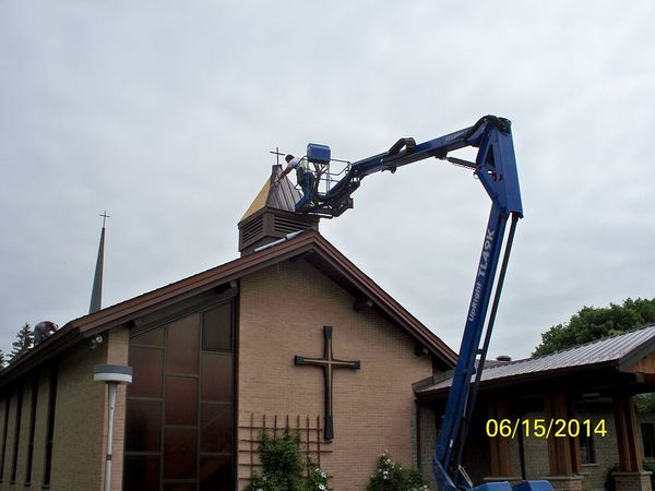 blue crane lifting worker to renovate roof of church
