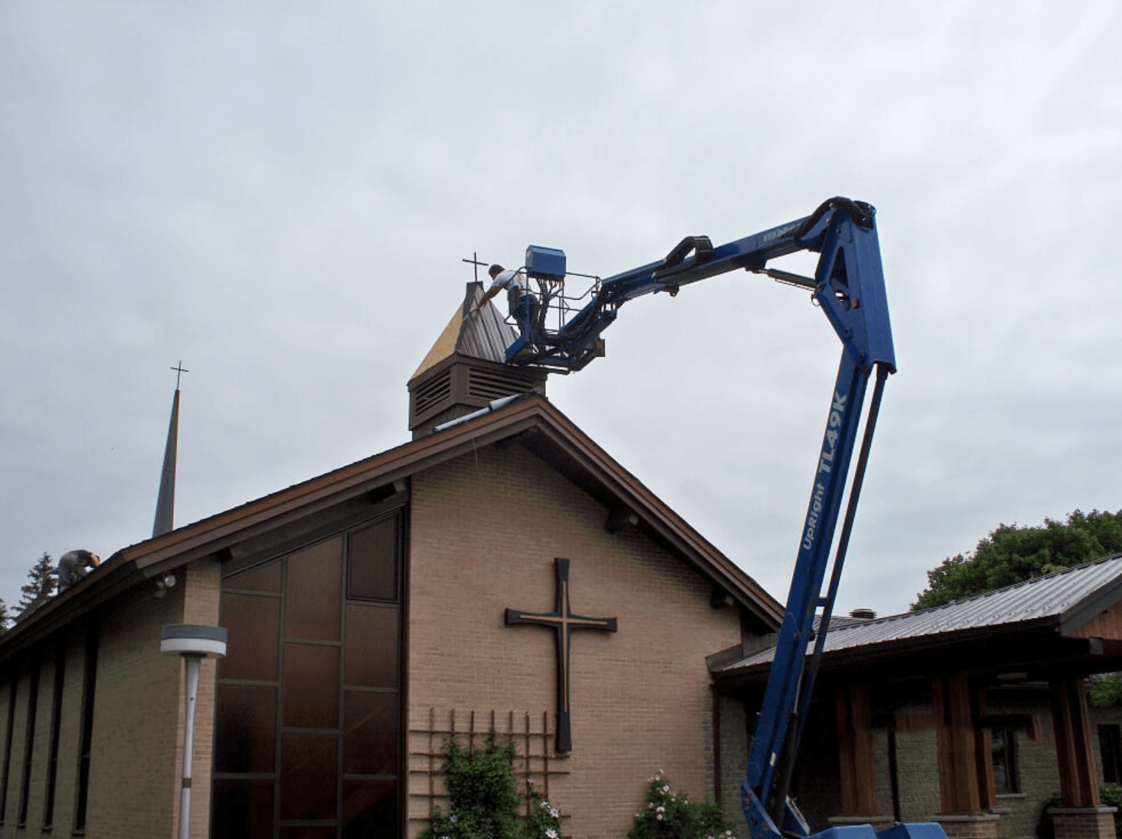 blue crane lifting worker to renovate church roof