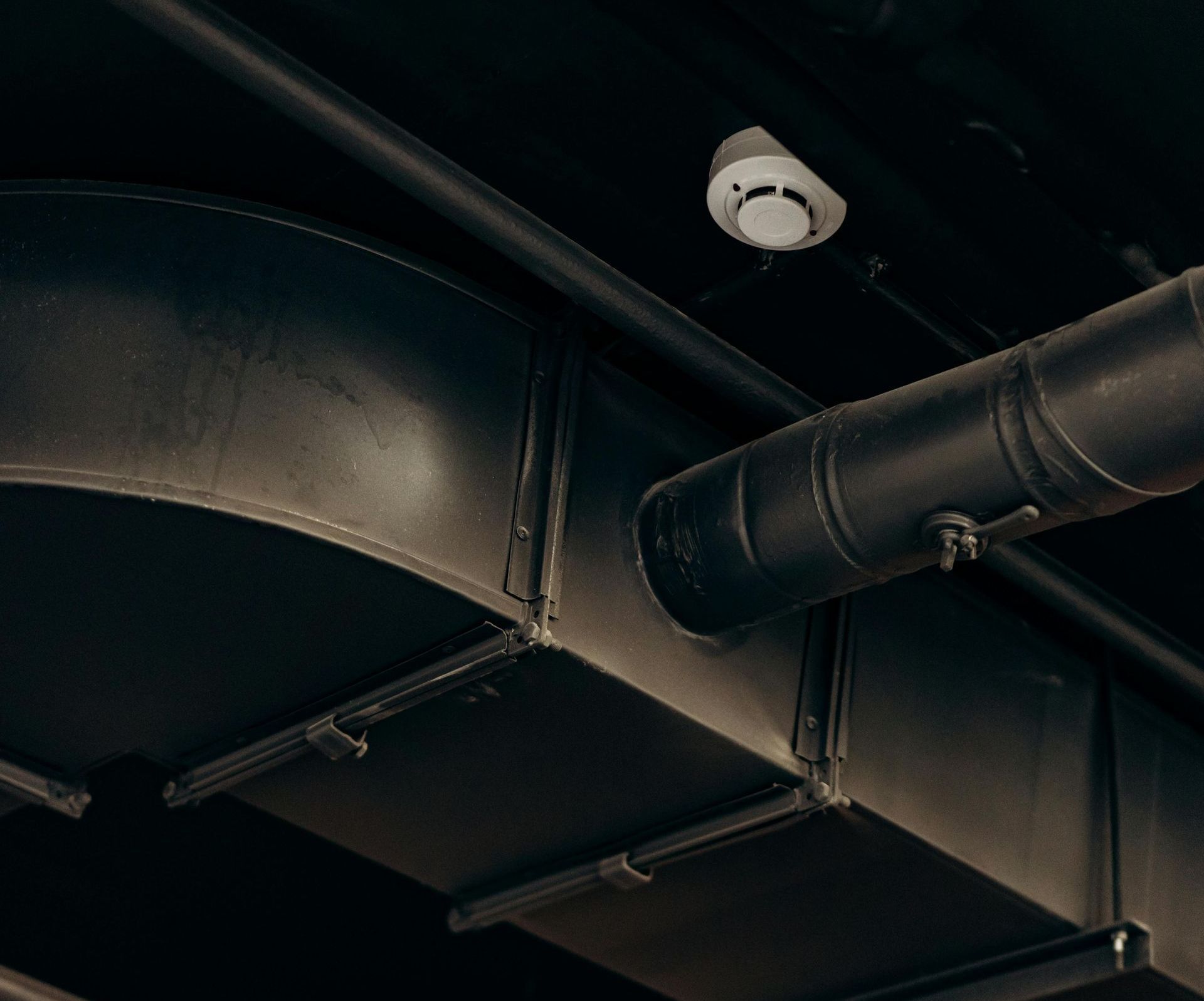 A smoke detector is hanging from the ceiling of a building.