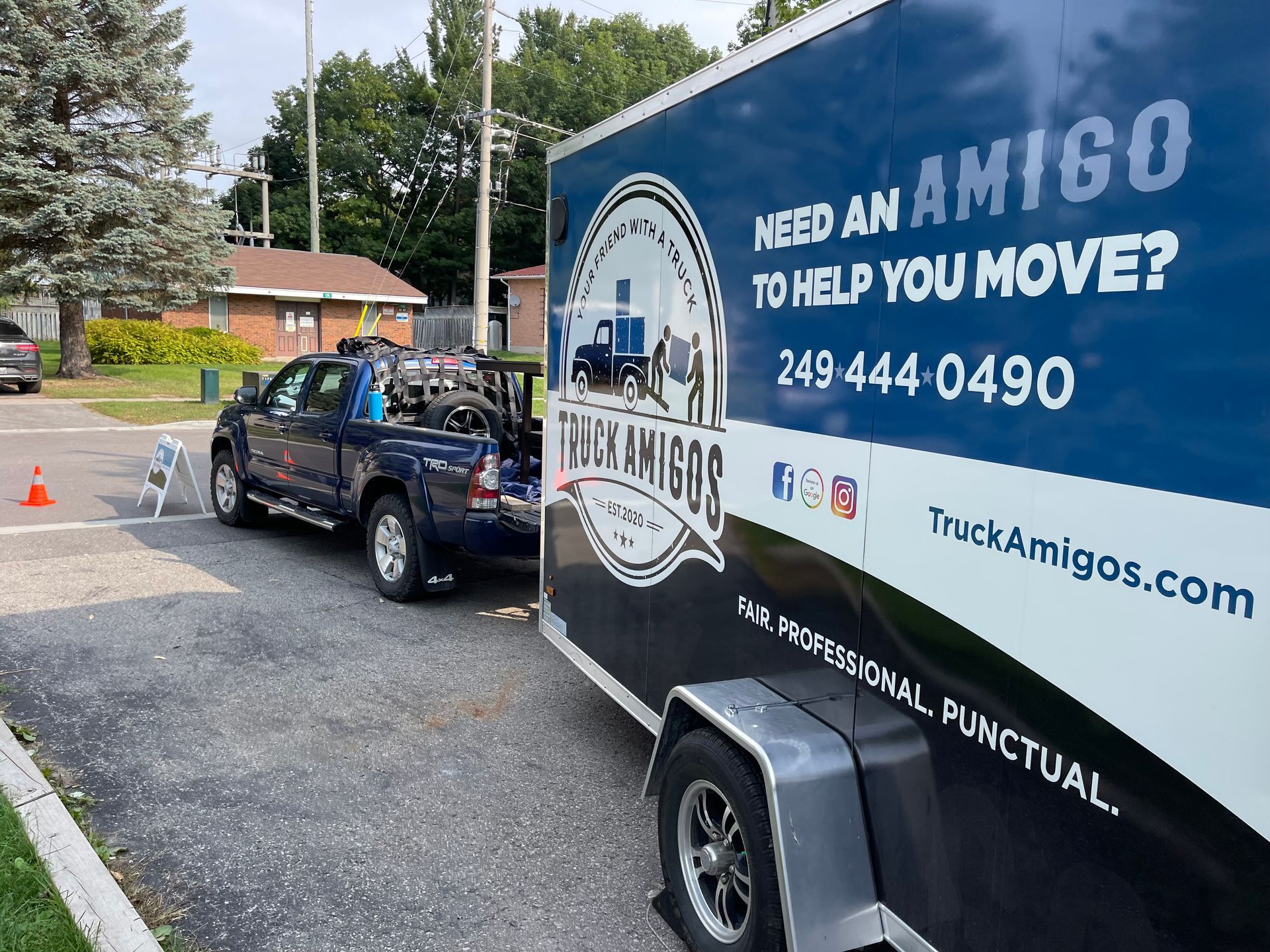 A truck is parked next to a trailer that says need an amigo to help you move