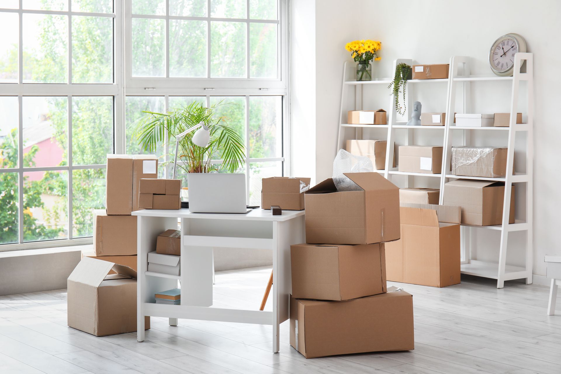 A room filled with boxes and a desk with a laptop on it.