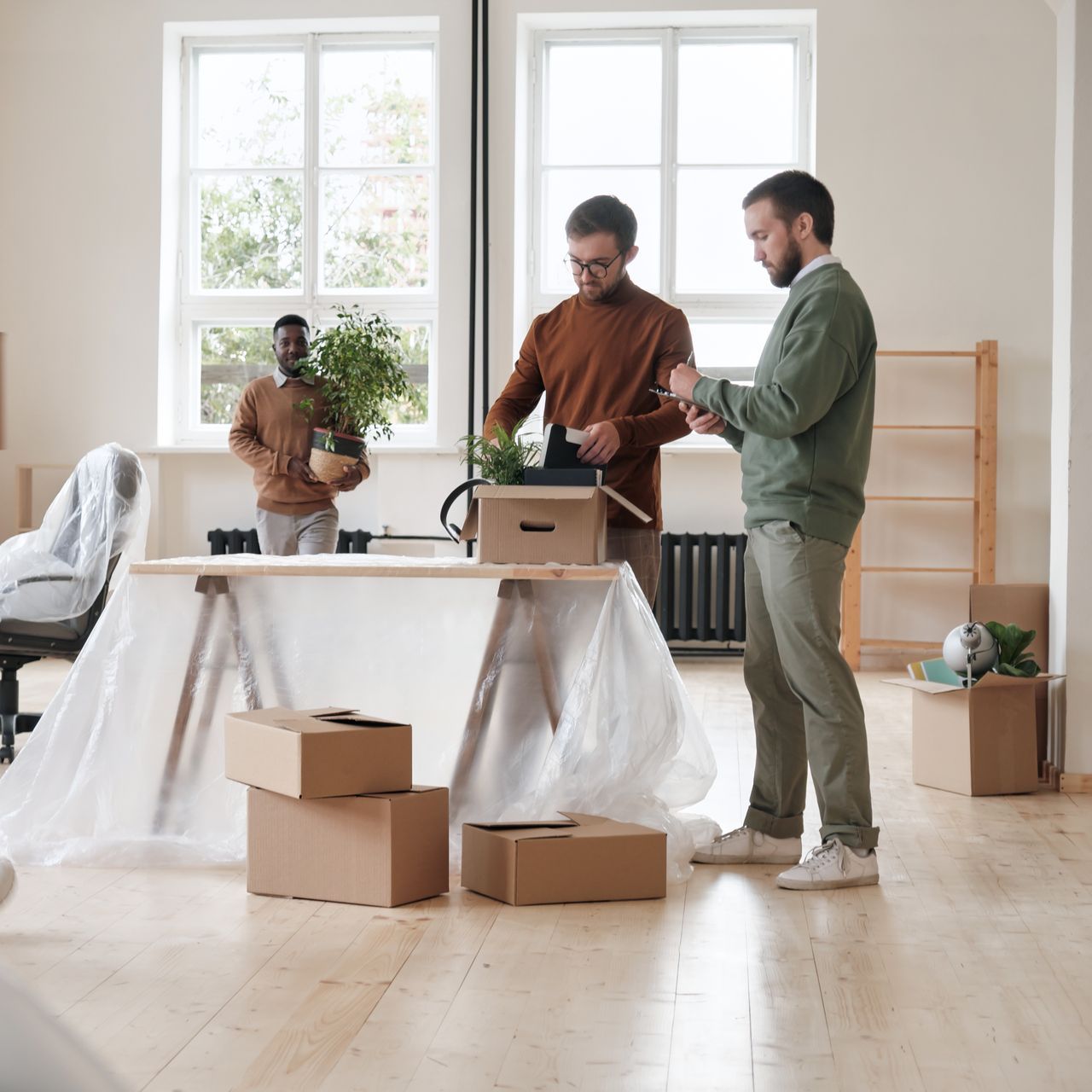 Two men are standing in a room with boxes and a table.