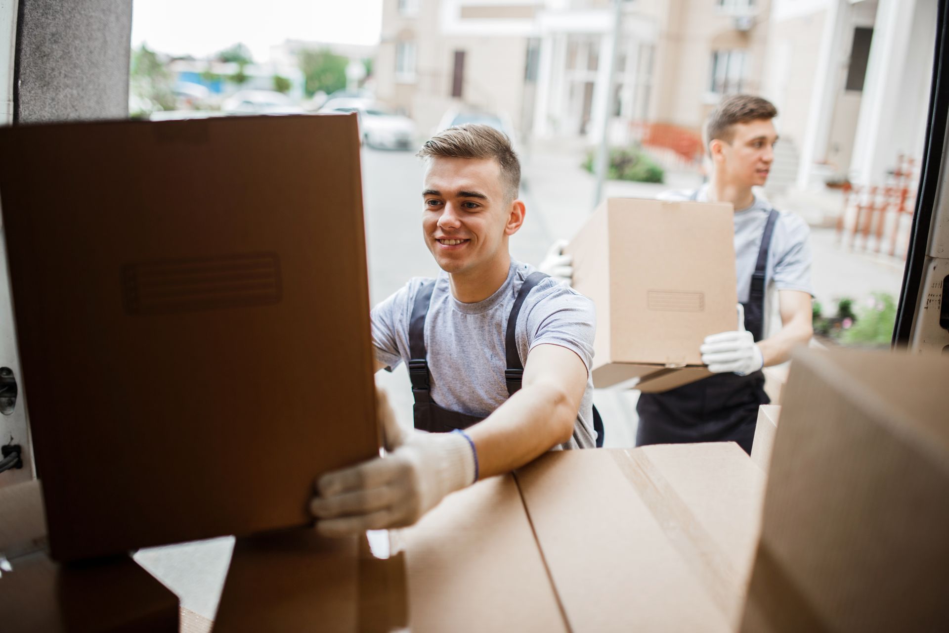 Two men are carrying boxes out of a van.