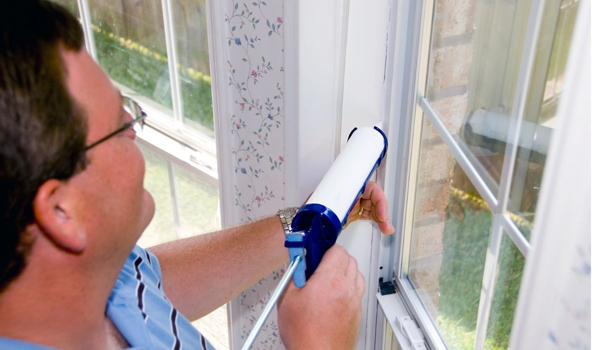 tech in home caulking windows to prevent leaky drafts.
