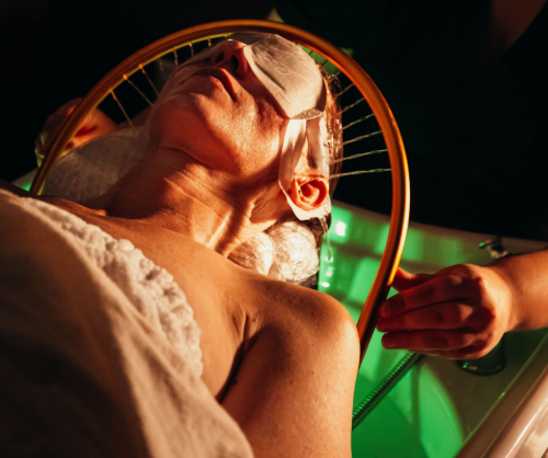 A person lies with their eyes covered while a professional holds a circular, wire-strung frame over their face.