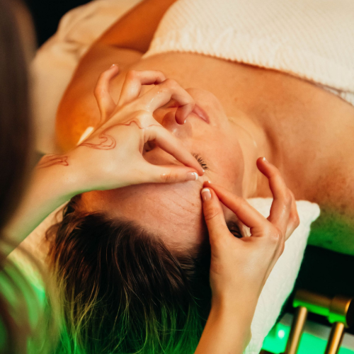 A practitioner performs a focused facial massage, applying precise pressure to a client’s forehead in a spa setting.